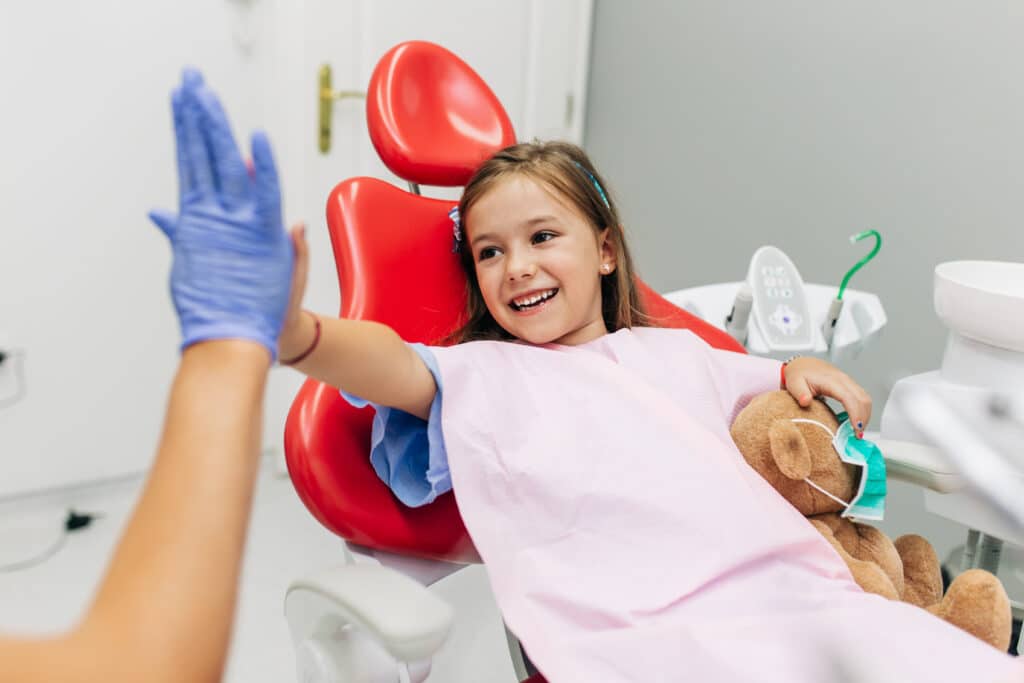 Smiling young patient high-fiving our pediatric dentist in Dubai